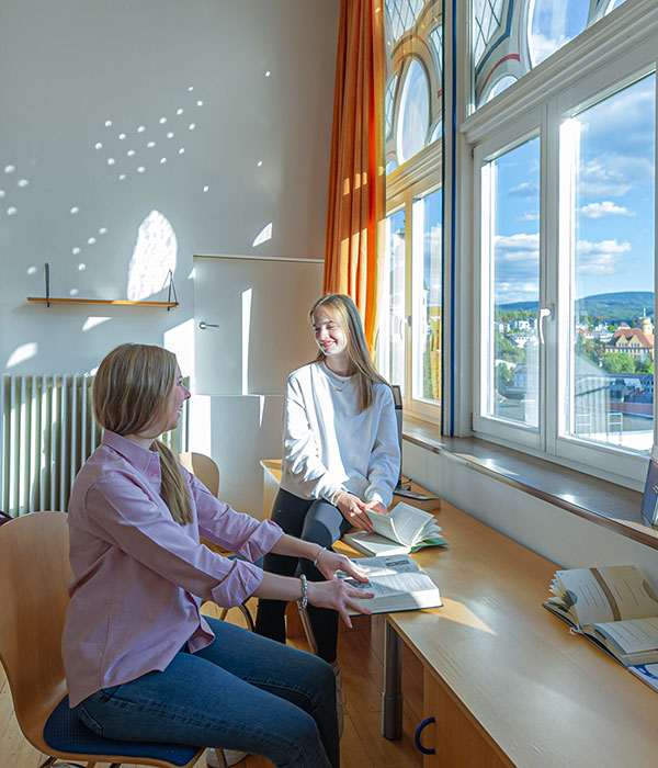 paedagogium_ganztages-konzept Zwei junge Schülerinnen sizen am Fenster im Pädagogium Baden-Baden